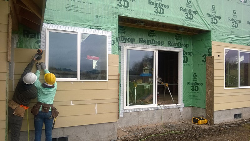 Spencer Anderson and Chelsea Koh install siding.