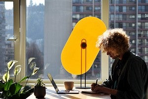 Photo of a person at a desk with a task shade
