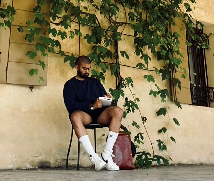 Yash notetaking in front of a yellowed concrete building
