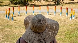 Photo of a women in a hat looking at an art installation outside