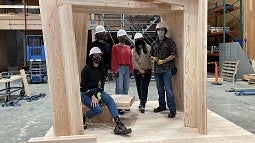 A team of student's posing in a wooden structure they created.