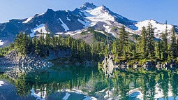 View of mountains and trees reflecting in a blue lake