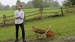 man with a wooden wheelbarrow in a field