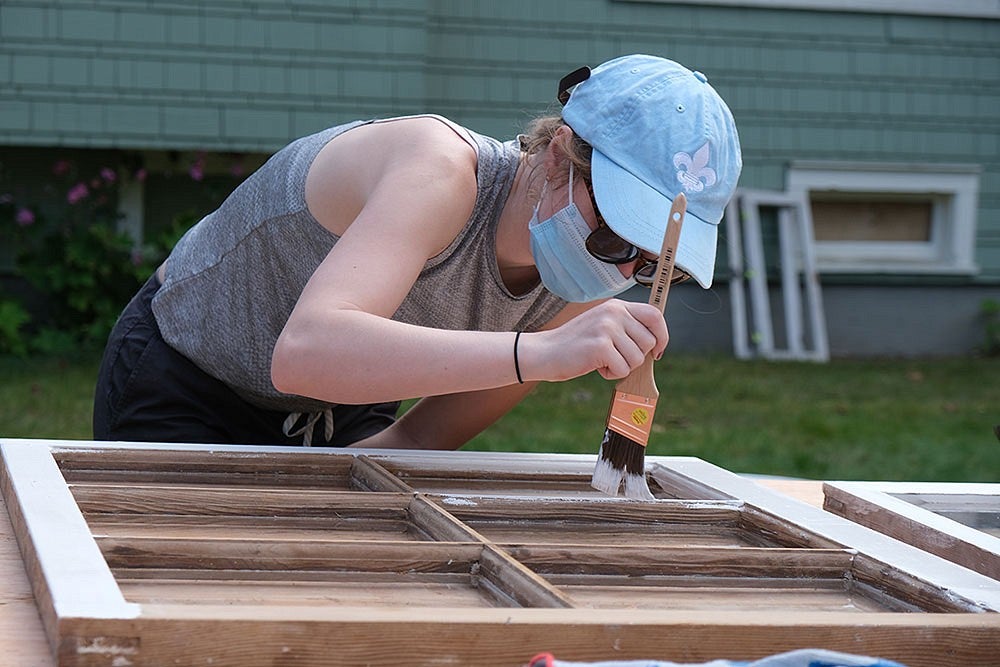 student painting window frame