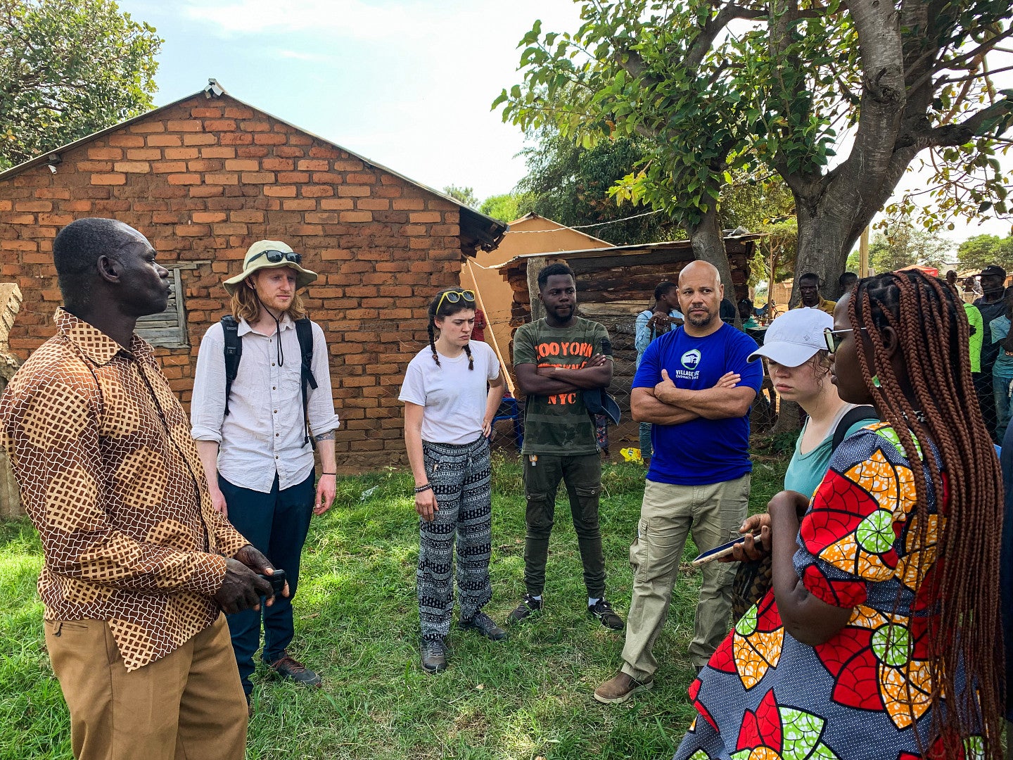 Photo of villagers, students from UO and Cincinnati, and Dr. Chris Lewis meeting together to discuss various projects.