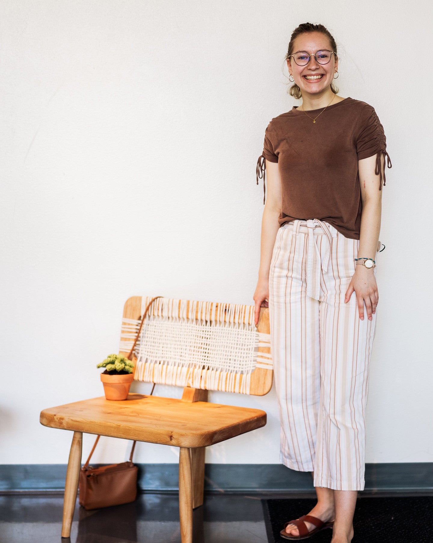 Alison standing with a 3-legged chair she designed for furniture studio.