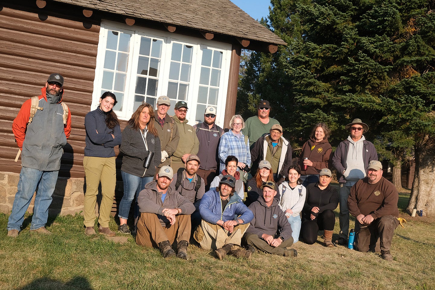 Photo from 2022 PNWPFS group shot in front of a log cabin. 