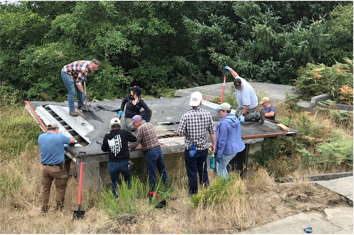 Action photo of the PNWPFS team working outside on a wooden structure.