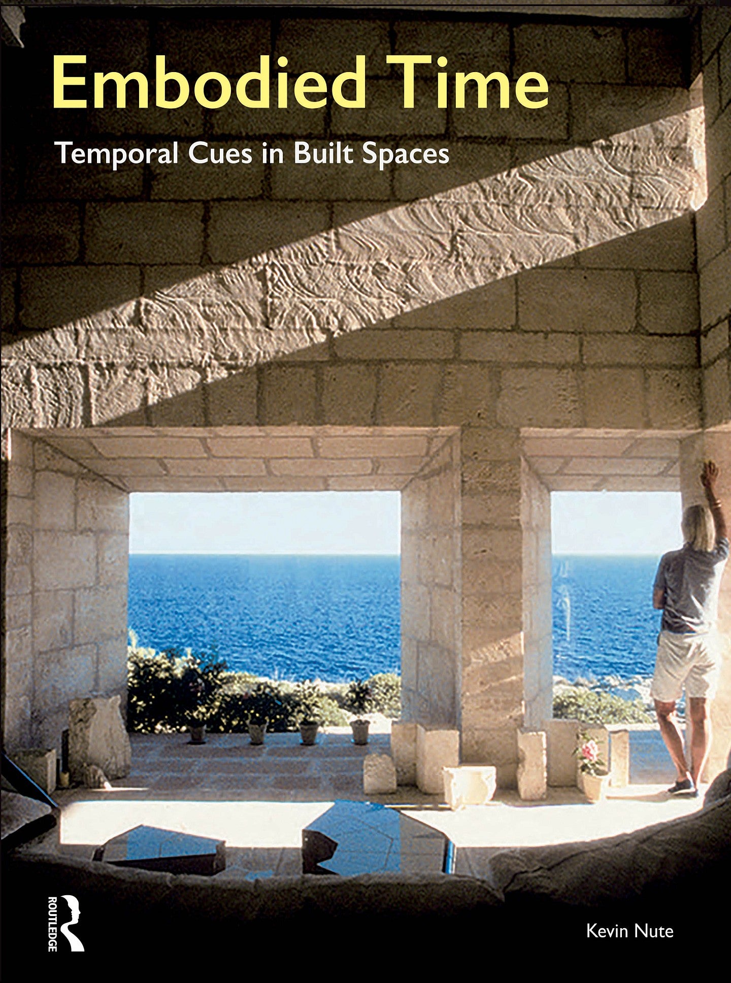 Cover for the Embodied Time book by Kevin Nute. Shows an interior stone space with open windows and a man leaning against an opening that opens into an ocean view. 