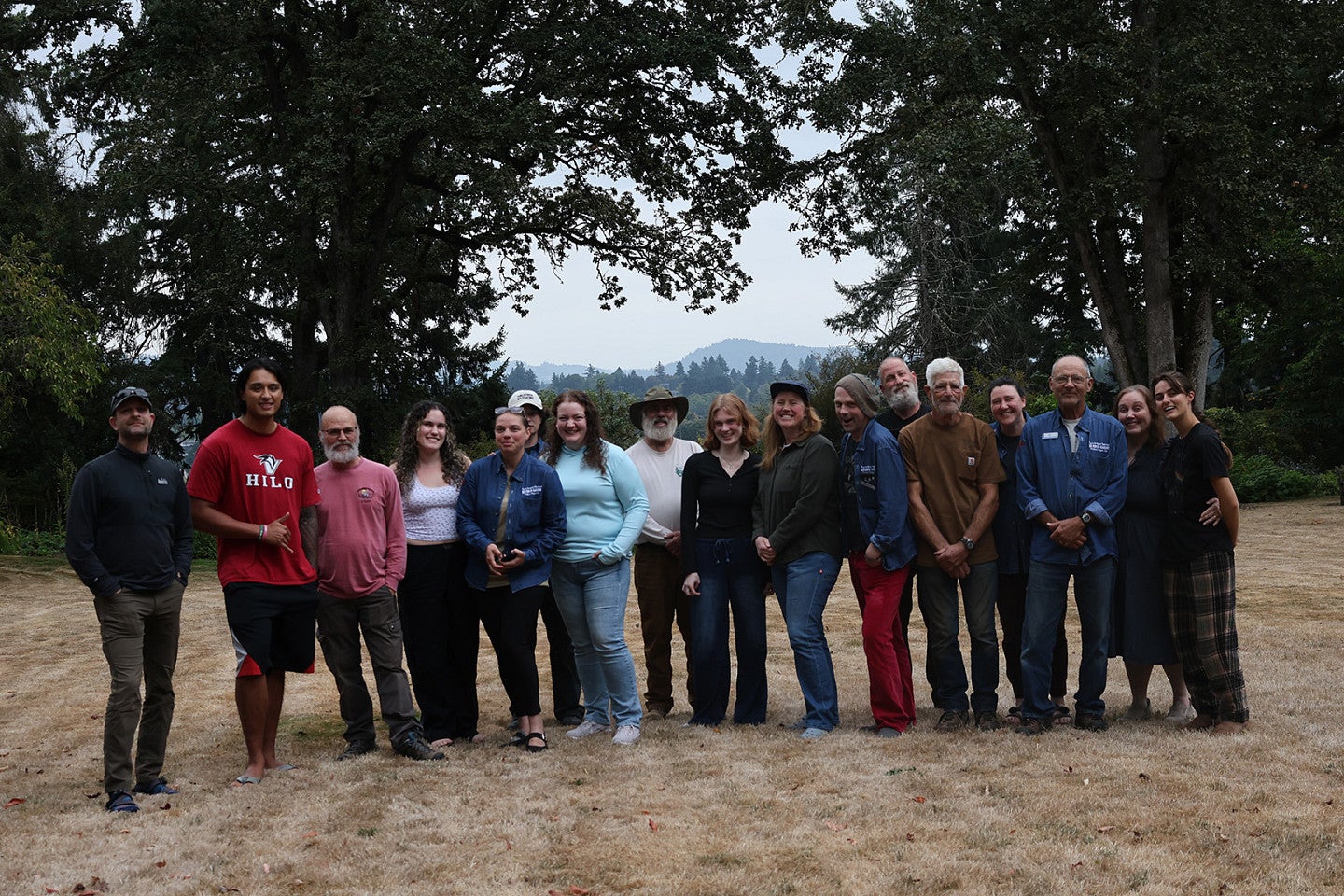 Students and Preservationists pose in front of a scenic scene of Oregon trees and mountains and hills. 