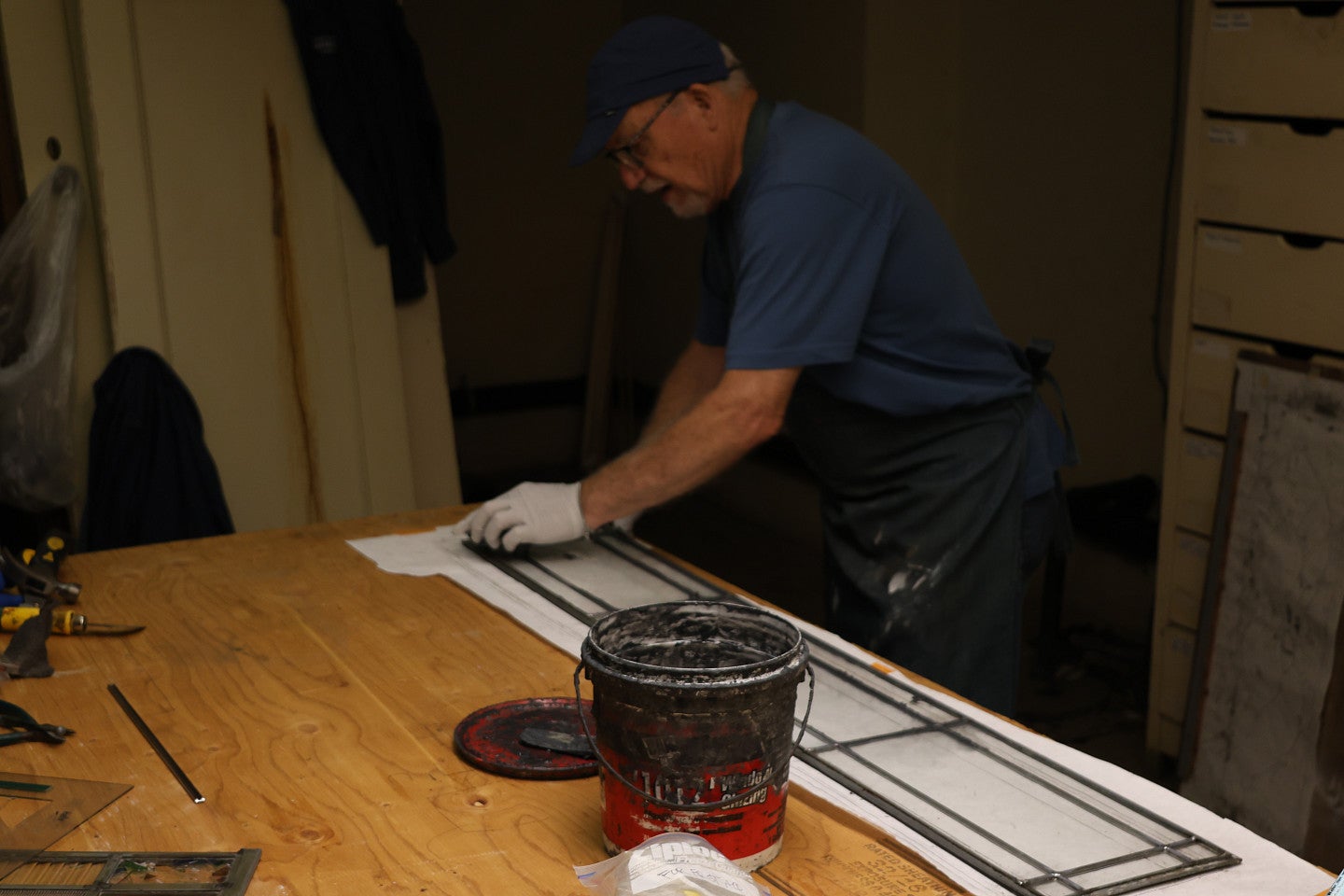Preservationist works on a stained glass panel inside a historic room/house.