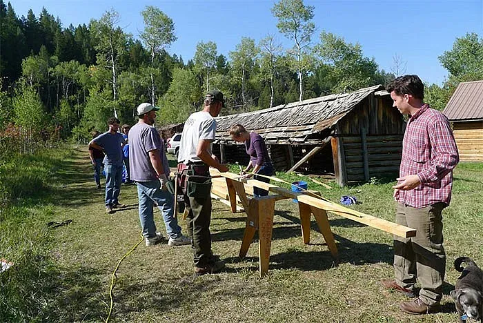 Students working with lumber outside a barn