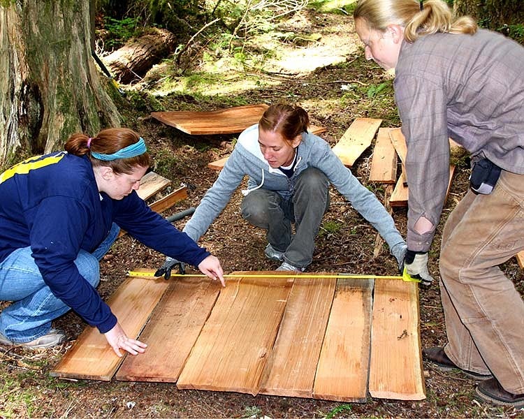 three students measure wood at field school