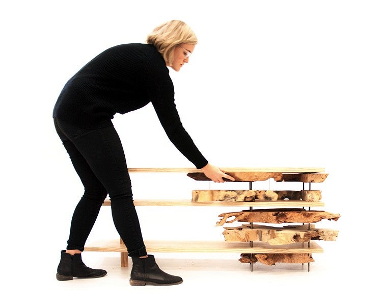 woman inspects table with tree slices