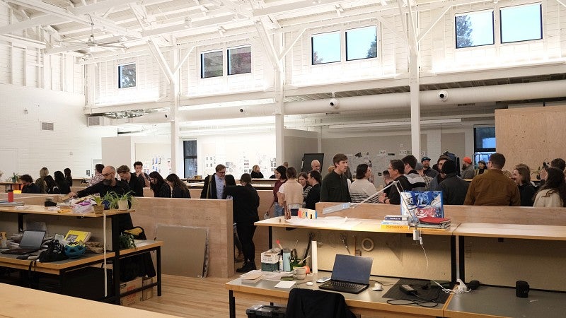 Shot of a crowd of students and professionals conversing in Highland Hall. 