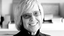 Black and white photo of Paulett Taggart, FAIA. Shows an older woman with short hair and glasses smiling into the camera.