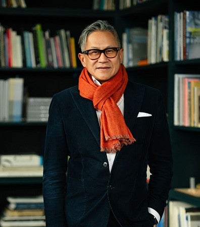 Design Partner at ZGF, Gene Sandoval, poses in front of a collection of books.