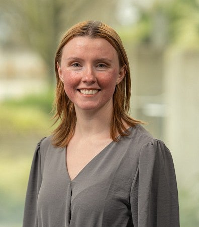 Tasha Hunter is staring into a camera with a smile and a soft background. 