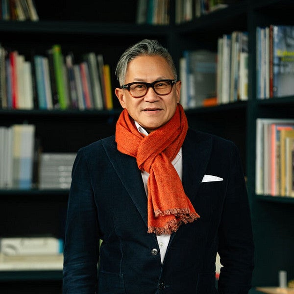 Design Partner at ZGF, Gene Sandoval, poses in front of a collection of books. 
